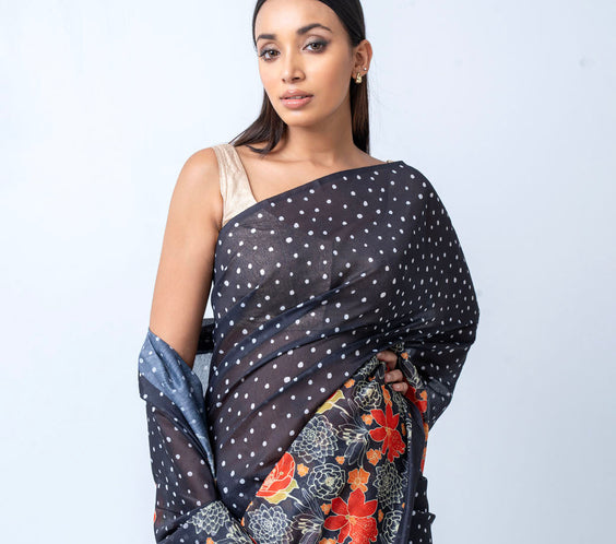 Woman wearing a black saree with floral patterns on a white background