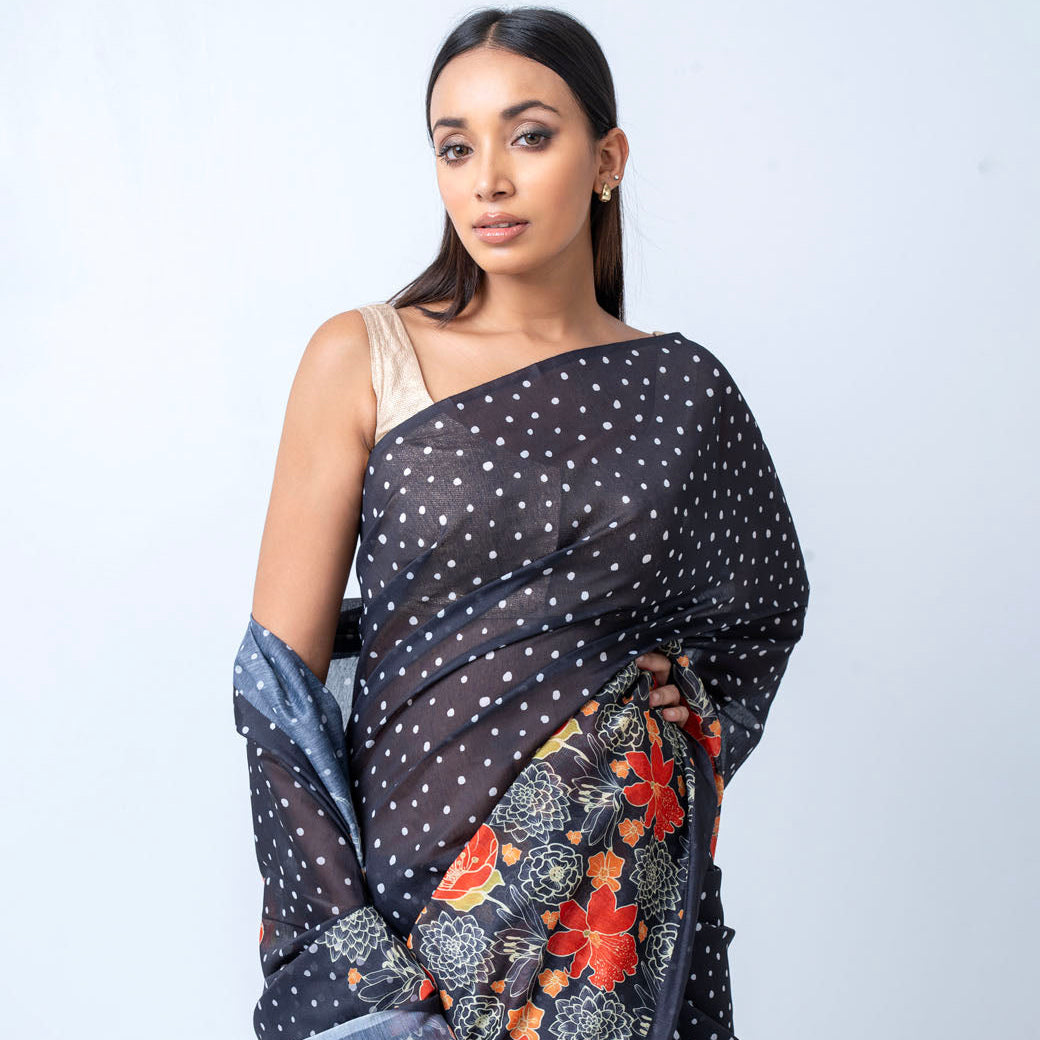 Woman wearing a black saree with floral patterns on a white background